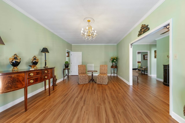 sitting room featuring ceiling fan with notable chandelier, light wood-type flooring, and ornamental molding