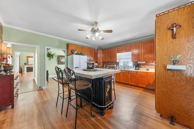 kitchen featuring a breakfast bar, a center island, white fridge with ice dispenser, and light wood-type flooring