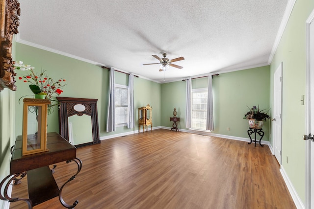 interior space featuring a textured ceiling, ceiling fan, wood-type flooring, and crown molding