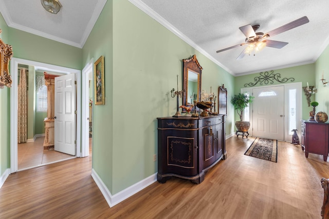 entryway featuring ceiling fan, light hardwood / wood-style floors, ornamental molding, and a textured ceiling