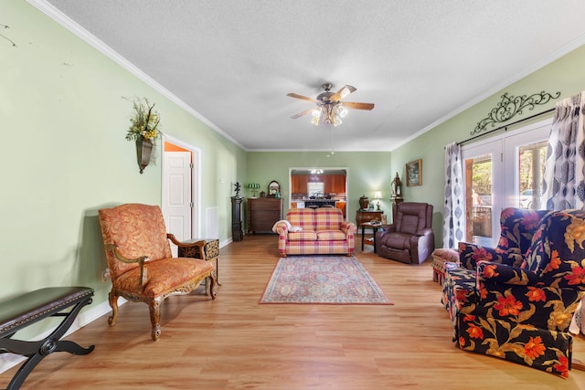 living room with ceiling fan, light hardwood / wood-style floors, a textured ceiling, and ornamental molding