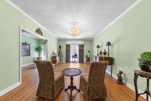 dining room with a textured ceiling, ornamental molding, a notable chandelier, and light wood-type flooring