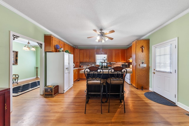 kitchen featuring a kitchen bar, light wood-type flooring, ornamental molding, white refrigerator with ice dispenser, and a kitchen island