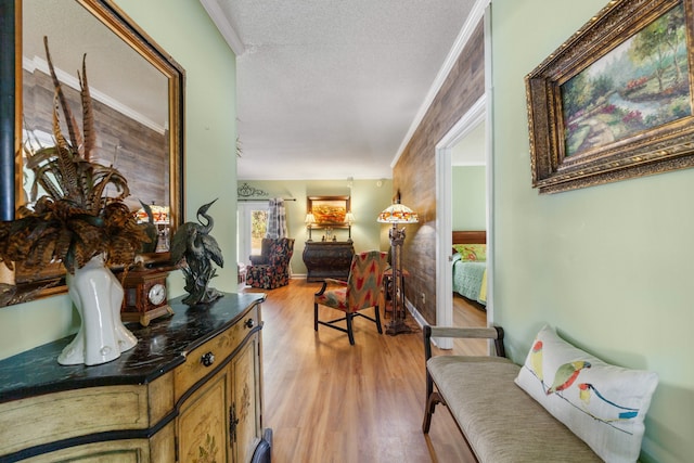 hallway with wood walls, ornamental molding, a textured ceiling, and light wood-type flooring