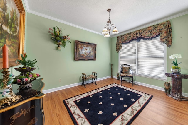 sitting room with hardwood / wood-style floors, a textured ceiling, crown molding, and a notable chandelier