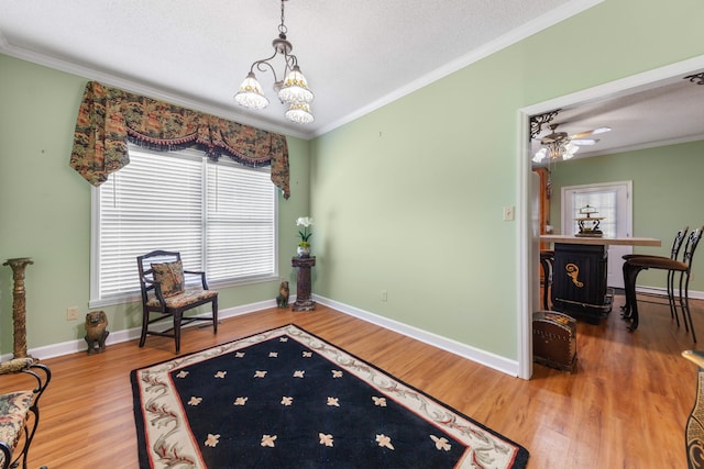 sitting room featuring hardwood / wood-style floors, ceiling fan with notable chandelier, and crown molding