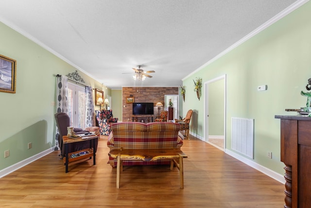 living room with a textured ceiling, light hardwood / wood-style flooring, ceiling fan, and ornamental molding