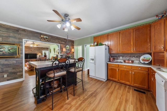 kitchen with white appliances, wooden walls, light hardwood / wood-style flooring, and ornamental molding