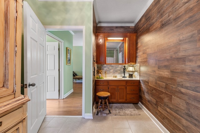 bathroom featuring wooden walls, tile patterned floors, decorative backsplash, vanity, and ornamental molding