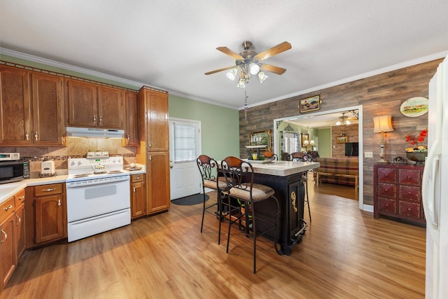 kitchen with a kitchen bar, light hardwood / wood-style flooring, white electric range oven, and ornamental molding