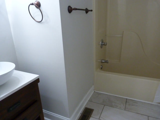 bathroom featuring tile patterned flooring, vanity, and bathing tub / shower combination