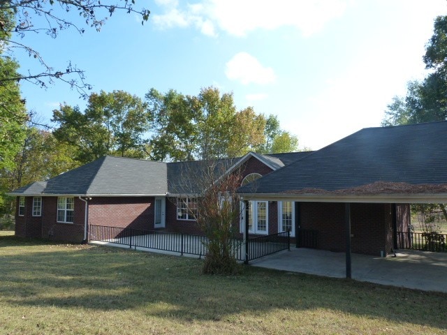 rear view of property featuring a lawn and a patio