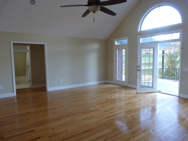 empty room featuring light wood-type flooring, high vaulted ceiling, and ceiling fan