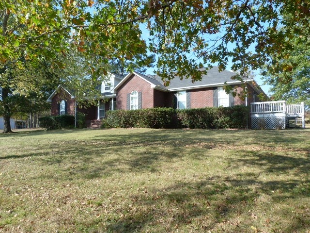 view of front of property with a wooden deck and a front yard