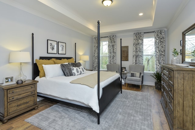 bedroom featuring dark hardwood / wood-style floors, ornamental molding, and a raised ceiling