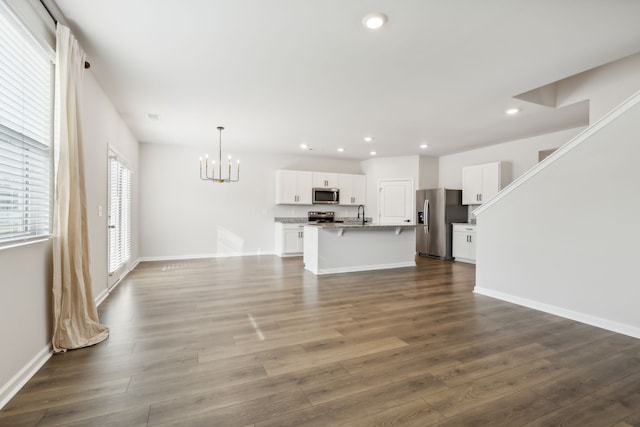 unfurnished living room featuring sink, dark hardwood / wood-style flooring, and an inviting chandelier