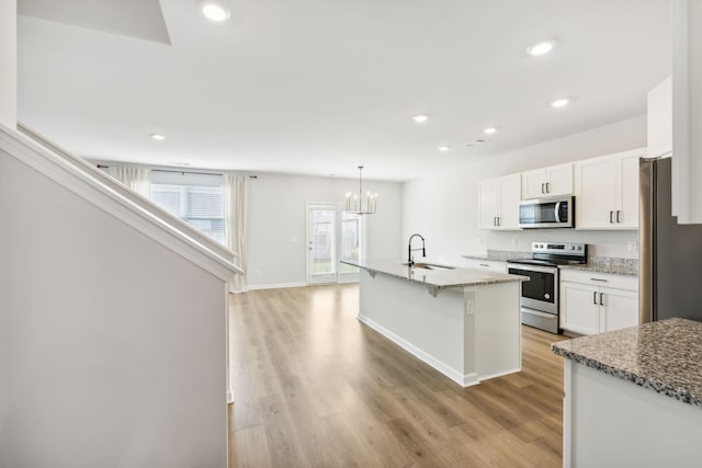 kitchen featuring appliances with stainless steel finishes, light wood-type flooring, a kitchen island with sink, sink, and white cabinets