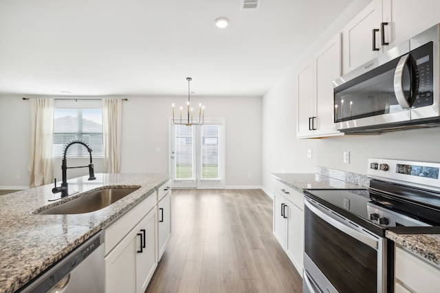 kitchen featuring appliances with stainless steel finishes, white cabinetry, a healthy amount of sunlight, and sink