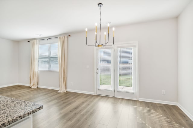 unfurnished dining area featuring light wood-type flooring and a chandelier