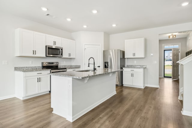 kitchen with white cabinetry, sink, wood-type flooring, a kitchen island with sink, and appliances with stainless steel finishes