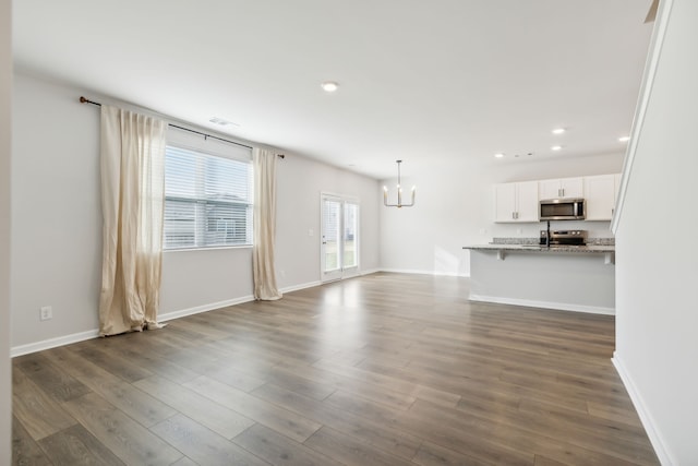 unfurnished living room featuring dark wood-type flooring and a notable chandelier