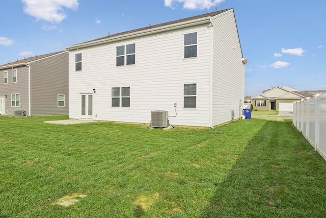 back of property featuring central air condition unit and a yard