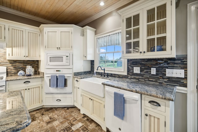 kitchen with sink, tasteful backsplash, dark stone countertops, white appliances, and ornamental molding