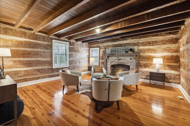 sitting room with wooden ceiling, a stone fireplace, wooden walls, light wood-type flooring, and beamed ceiling