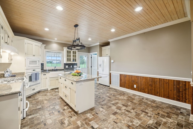 kitchen featuring decorative light fixtures, a center island, light stone counters, and white appliances