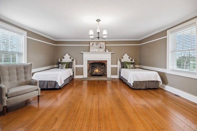 bedroom featuring a chandelier, wood-type flooring, a fireplace, and crown molding