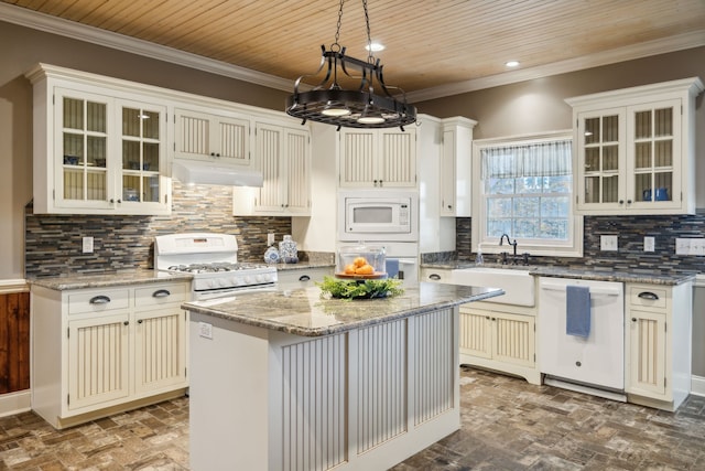 kitchen featuring backsplash, white appliances, sink, pendant lighting, and a center island