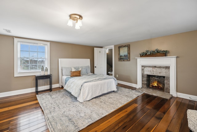 bedroom with dark hardwood / wood-style floors and a fireplace