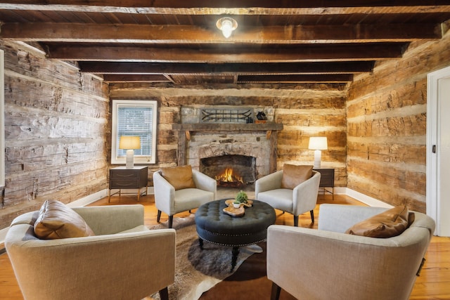 living area featuring beam ceiling, a stone fireplace, wood ceiling, and light hardwood / wood-style floors