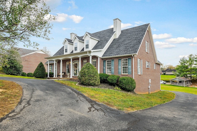 new england style home featuring a front yard and a porch