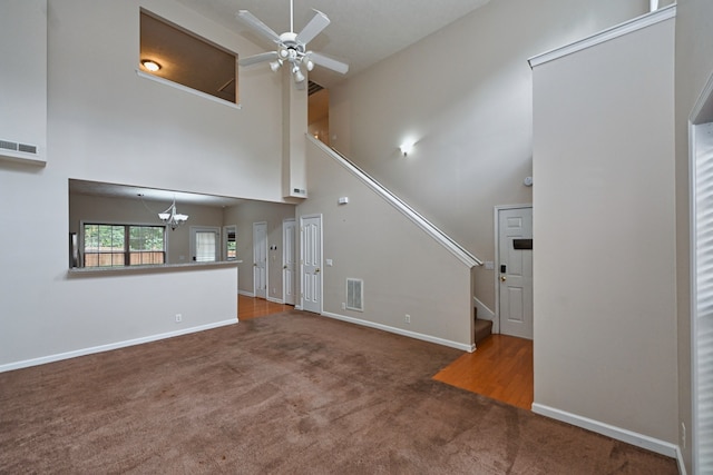 unfurnished living room featuring ceiling fan with notable chandelier, carpet floors, and high vaulted ceiling