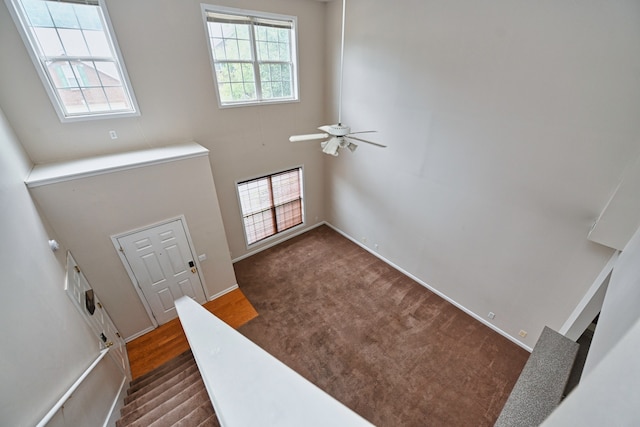 carpeted foyer entrance featuring ceiling fan and a towering ceiling