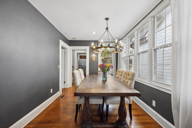 dining room with dark hardwood / wood-style floors and an inviting chandelier