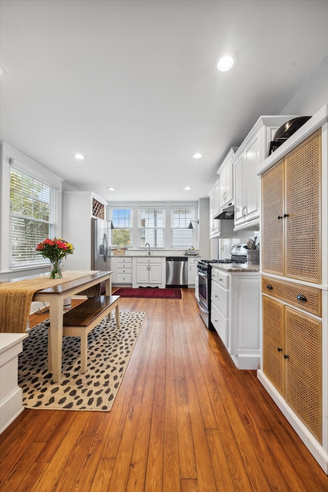 kitchen with sink, hardwood / wood-style floors, white cabinets, and appliances with stainless steel finishes