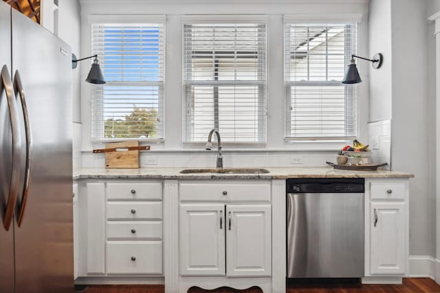 kitchen with white cabinetry, sink, light stone countertops, dark hardwood / wood-style flooring, and appliances with stainless steel finishes