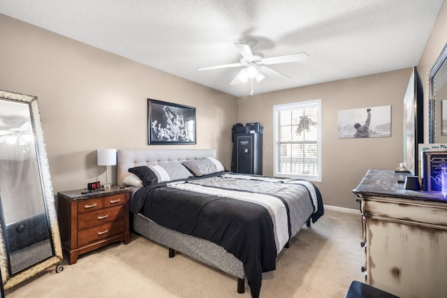 bedroom with ceiling fan, light colored carpet, and a textured ceiling