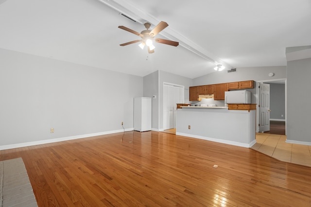 unfurnished living room featuring vaulted ceiling with beams, ceiling fan, and light wood-type flooring