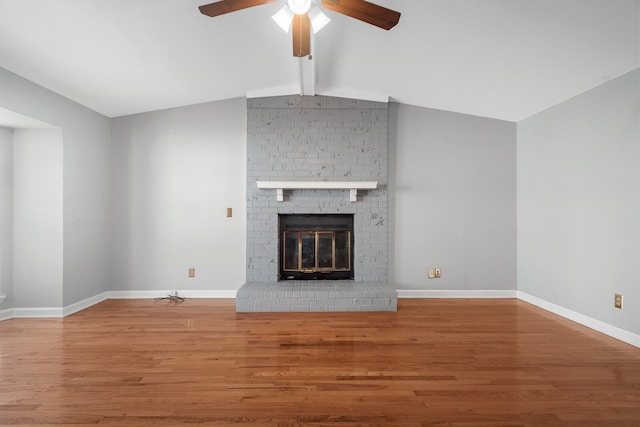 unfurnished living room with vaulted ceiling with beams, hardwood / wood-style flooring, a brick fireplace, and ceiling fan