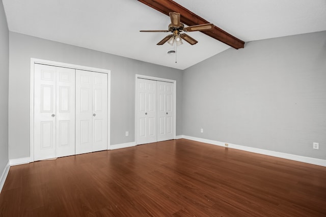 unfurnished bedroom with hardwood / wood-style flooring, ceiling fan, lofted ceiling with beams, and multiple closets