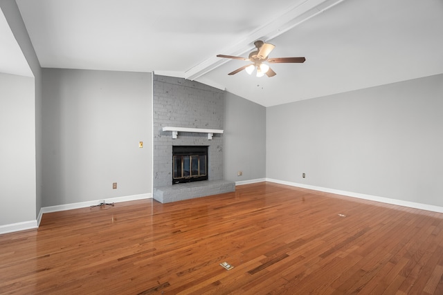 unfurnished living room featuring wood-type flooring, lofted ceiling with beams, a brick fireplace, and ceiling fan