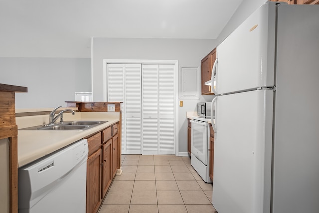 kitchen with light tile patterned floors, white appliances, and sink