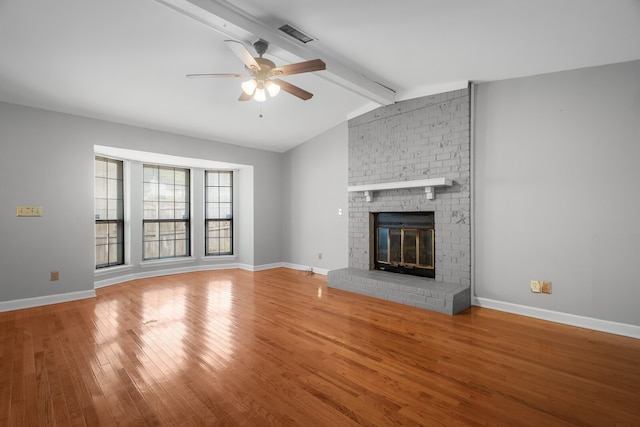 unfurnished living room with lofted ceiling with beams, ceiling fan, wood-type flooring, and a brick fireplace