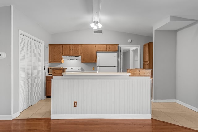 kitchen with stove, white refrigerator, light tile patterned floors, and vaulted ceiling