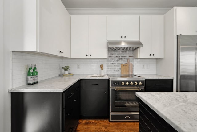 kitchen with electric range oven, white cabinetry, and exhaust hood