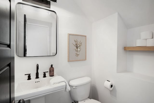 bathroom with toilet, sink, and vaulted ceiling