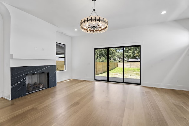 unfurnished living room with light wood-type flooring and a notable chandelier